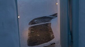 Un étroit passage entre les bâtiments, avec un portail en métal sur la droite.