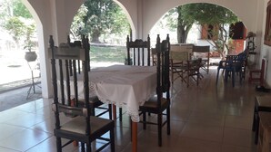 Zona de dinar amb taula preparada per a quatre, envoltada de cadires de fusta amb seients amb coixí.