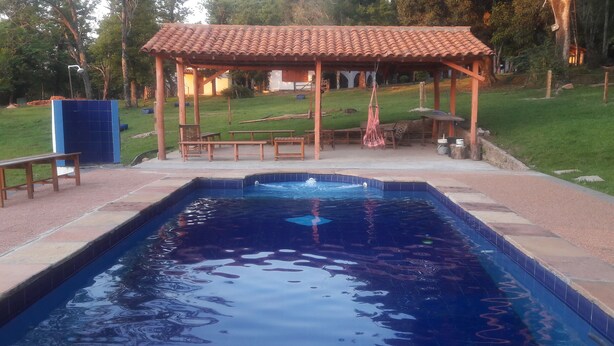 Una piscina amb un solàrium d'rajola, un porxo de fusta i taules de picnic.