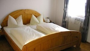 Een houten bed met witte lakens in een kamer met houten vloeren.