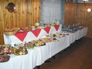 Une table de buffet garnie de divers plats et recouverte d’une nappe rouge et blanche.