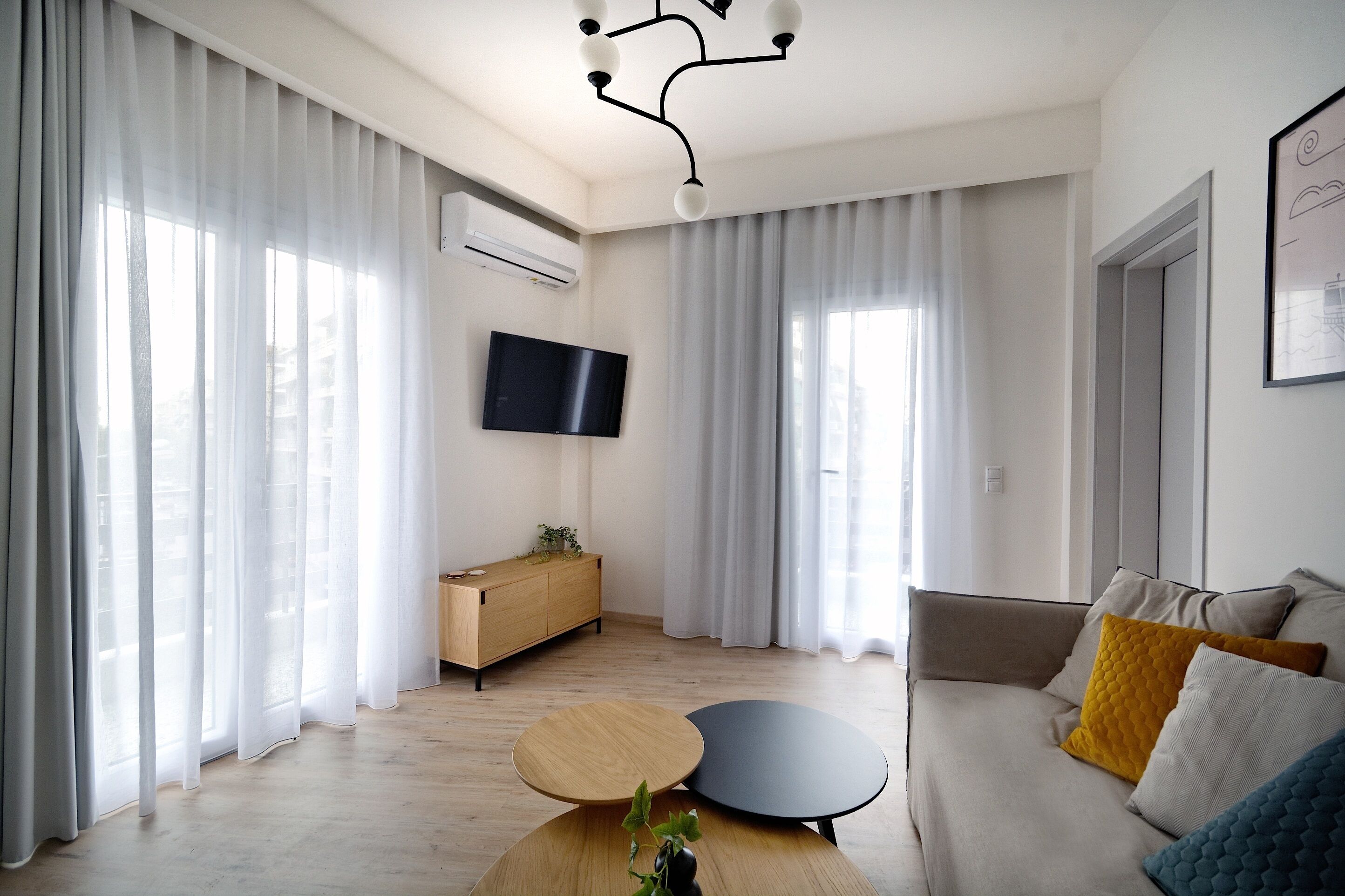 A modern living room with a sofa, a coffee table, and a TV mounted on the wall.