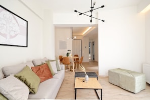 Un salon moderne avec un canapé, une table basse et, au fond, un coin repas.