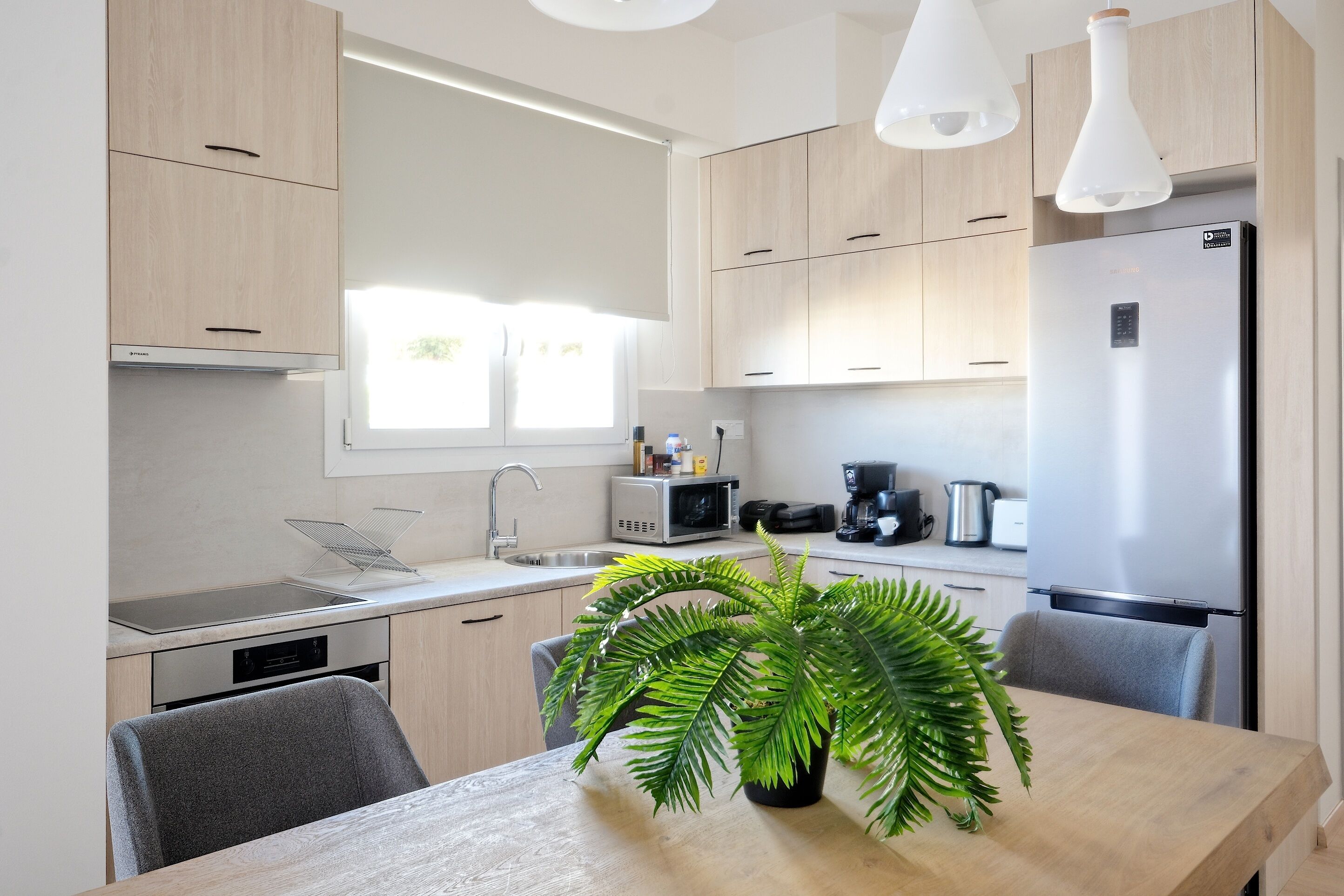 A modern kitchen with wooden cabinets, a stainless steel refrigerator, a microwave, and a sink.