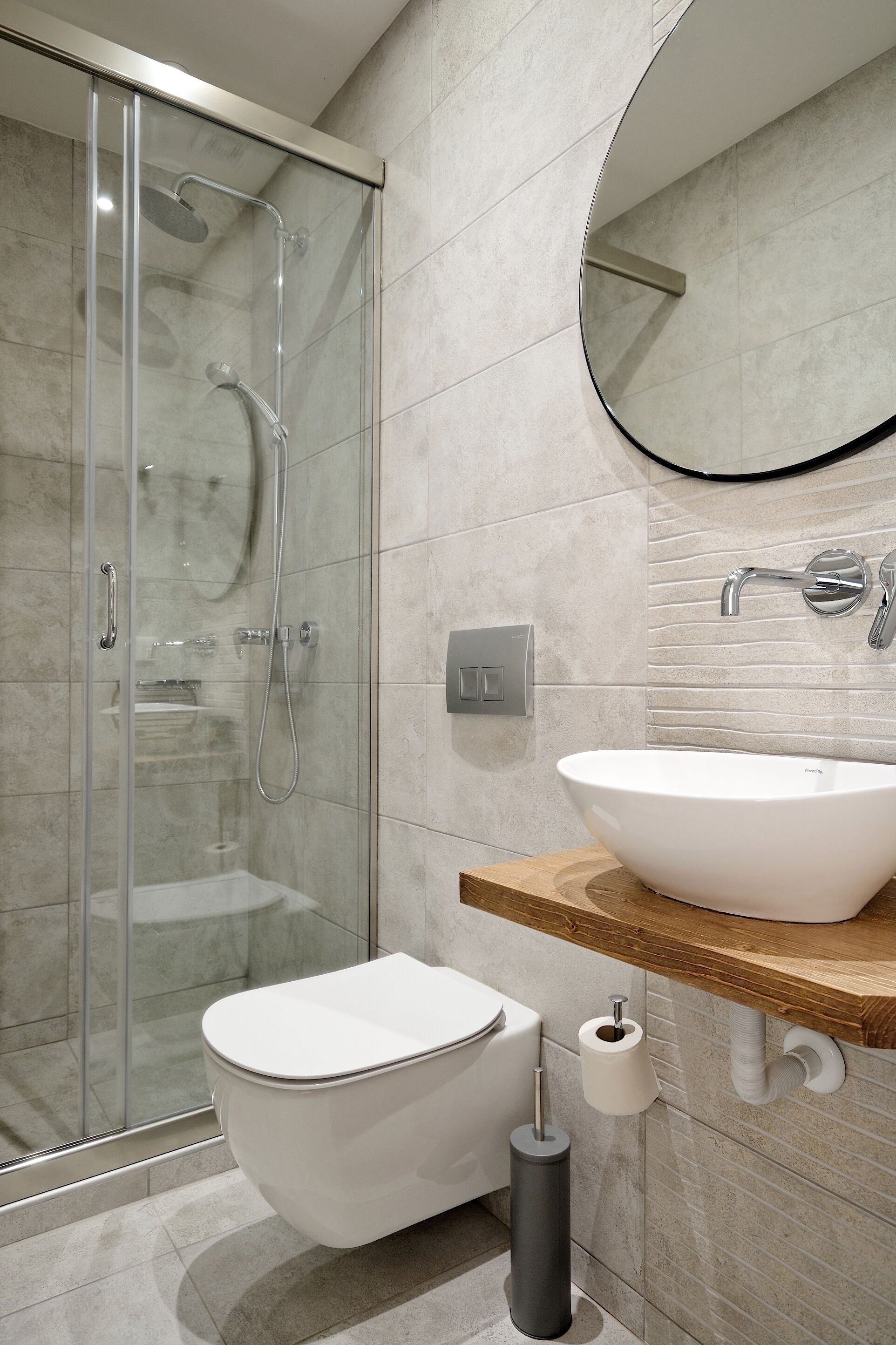 A modern bathroom with a glass-enclosed shower, a white toilet, and a wooden vanity with a white sink.
