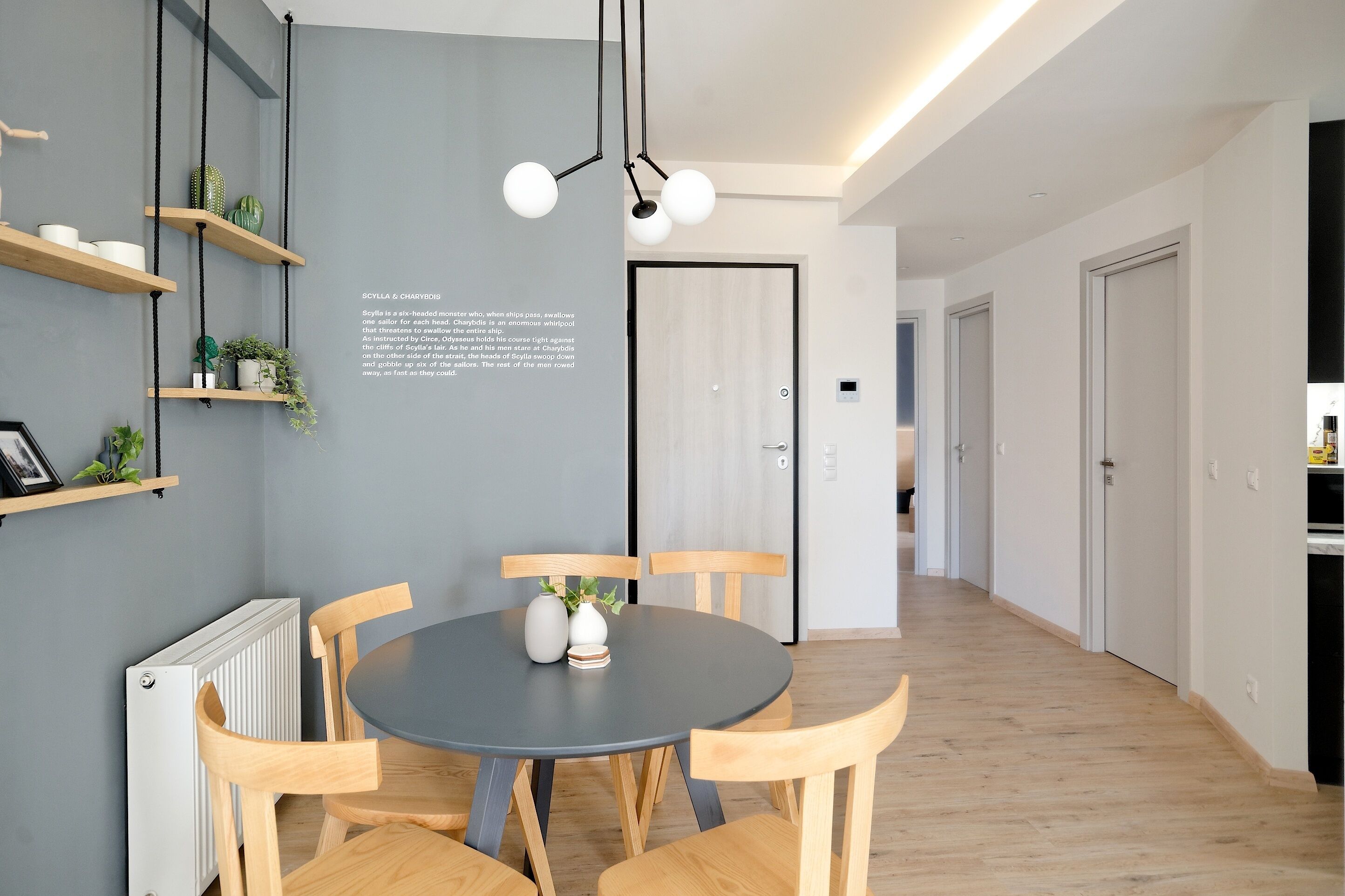 A modern dining area with a round table, wooden chairs, and a black ceiling light.