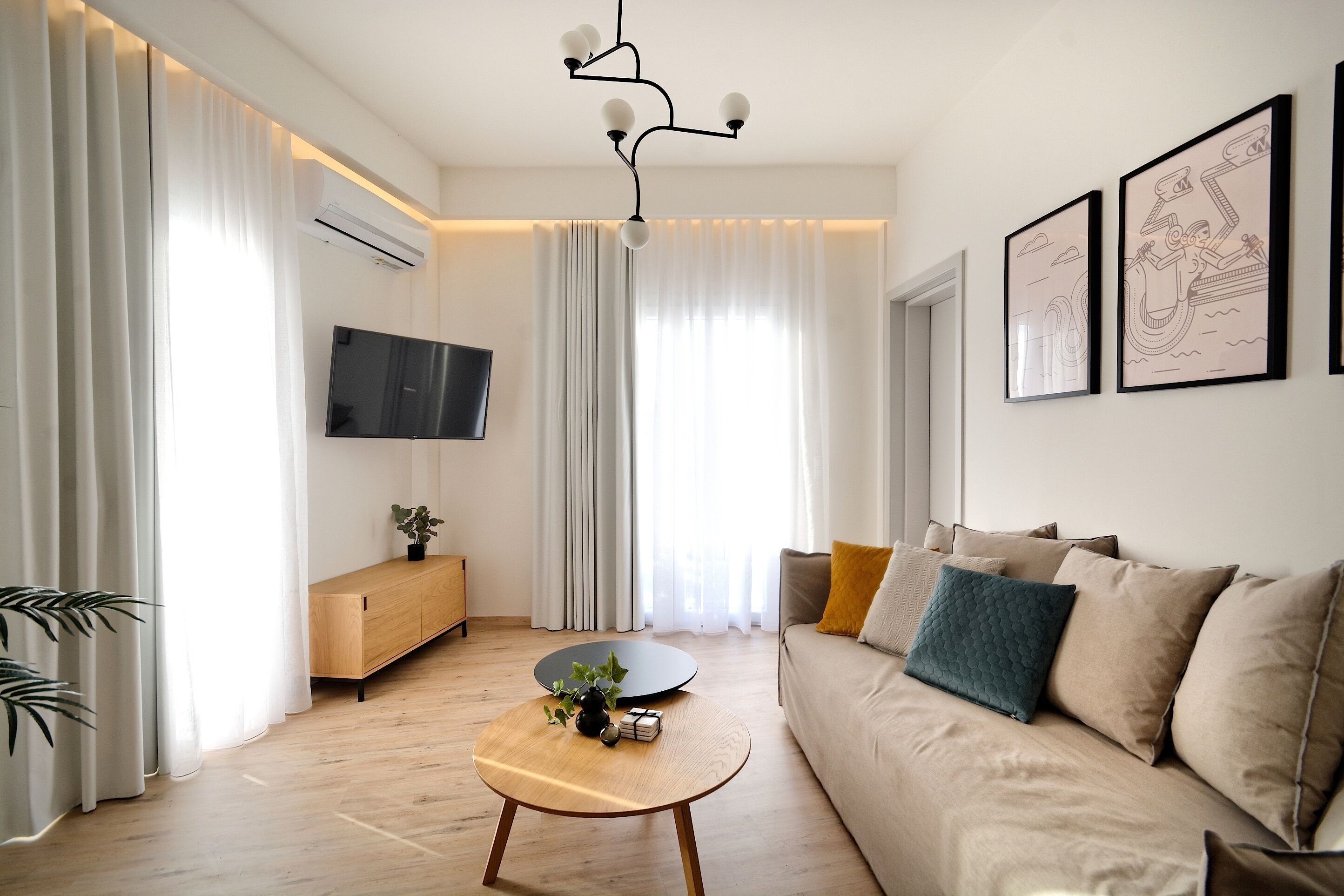 A modern living room with a wooden coffee table, a beige sofa, and a mounted flat-screen TV.