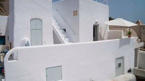Un bâtiment blanc avec un escalier, une porte et un parapluie.