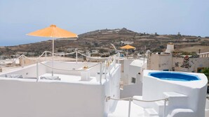 Une terrasse sur le toit avec des murs blancs, une piscine bleue et des parasols orange.