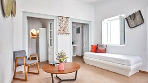 Un soggiorno moderno con un divano bianco, una sedia di legno e un tavolino rotondo con un vaso di fiori.