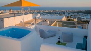 Una terrazza sul tetto con vasca idromassaggio, un ombrellone giallo e vista sulla città e sul mare.