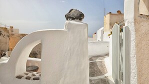 Un edificio dalle pareti bianche, con un viale in pietra e una grande roccia su un balcone.