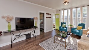 A living room with a flat-screen TV, a coffee table, and two blue armchairs.
