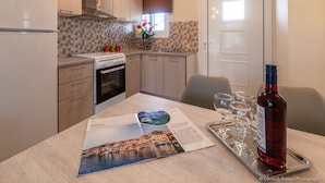 A modern kitchen with a dining area, featuring a magazine, wine bottle, and glasses on a tray. - Nancy's Luxury Apartments (Zakynthos)