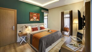 A modern hotel room with a large bed, a desk with a laptop, a TV, and a painting on the wall. - The Fox Hotel (Istanbul)
