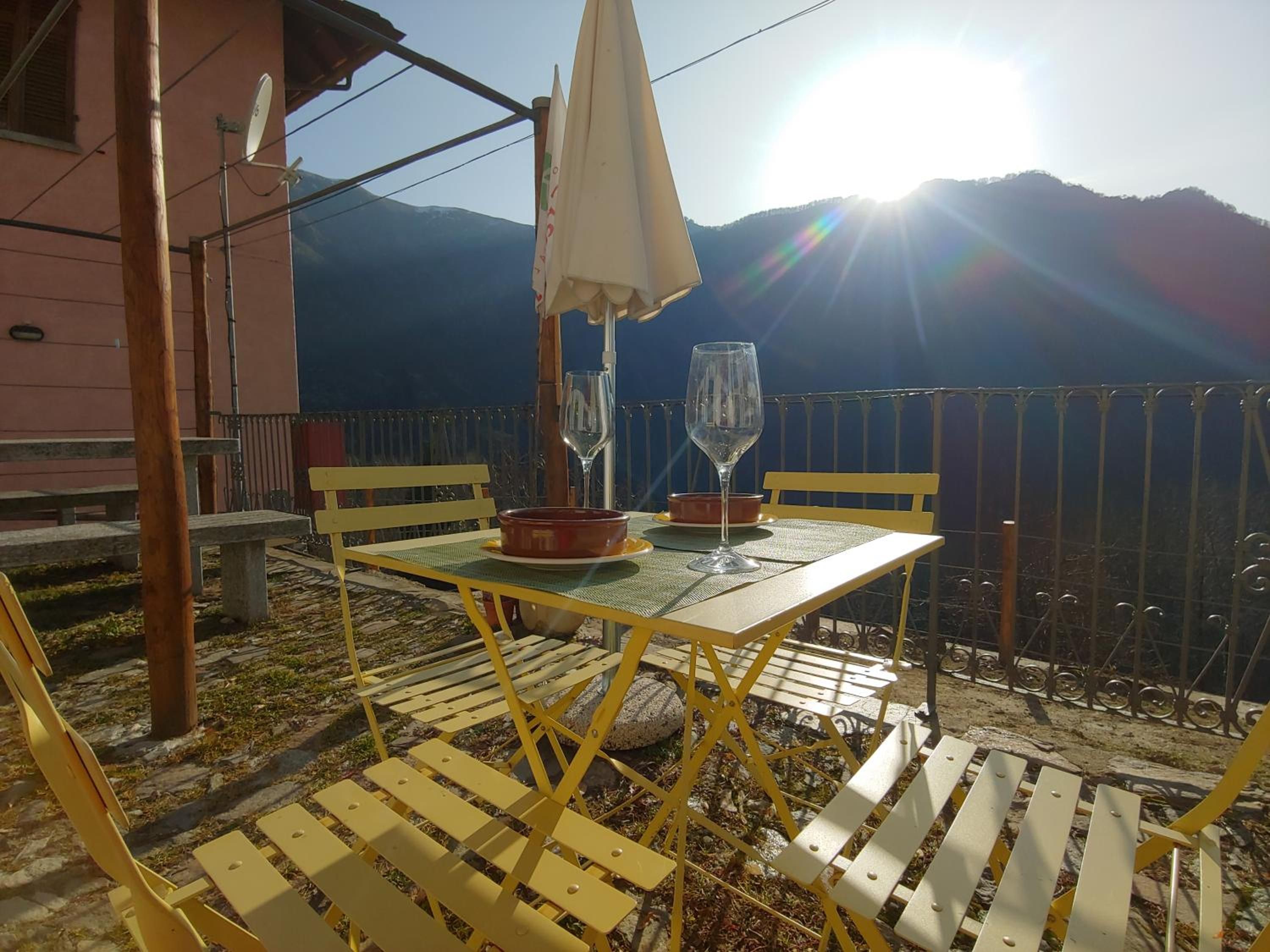 A table with two chairs and an umbrella, set against a mountainous backdrop.