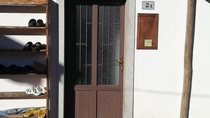 L’entrée d’un immeuble avec une porte marron, un porte-chaussures en bois et une plaque indiquant le numéro 2A.