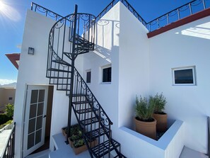 A white building with a black spiral staircase, potted plants, and a clear blue sky. - Casa Estrellas - private pool, amazing roof top view, and walk to local beach (Cabo San Lucas)
