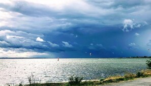 Escena costera con un cuerpo de agua, cielo nublado y una línea de costa distante.