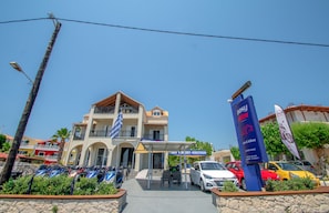 A hotel with a covered car park, multiple floors, and a balcony. - George Apartments (Zakynthos)