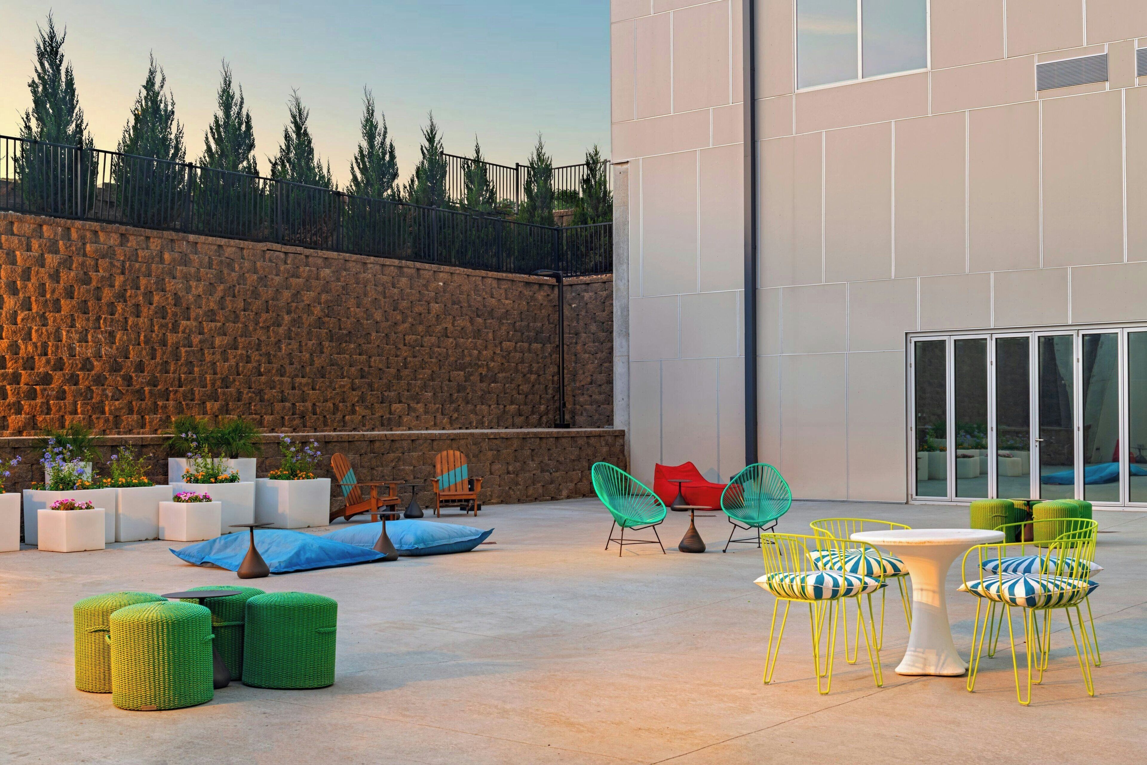 An outdoor patio with a stone wall, potted plants, and a mix of modern and classic outdoor furniture.