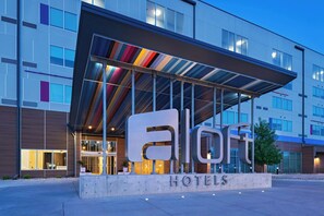 A modern hotel with a large illuminated sign reading "El Corte Hotels". - Aloft by Marriott Omaha West (Elkhorn)