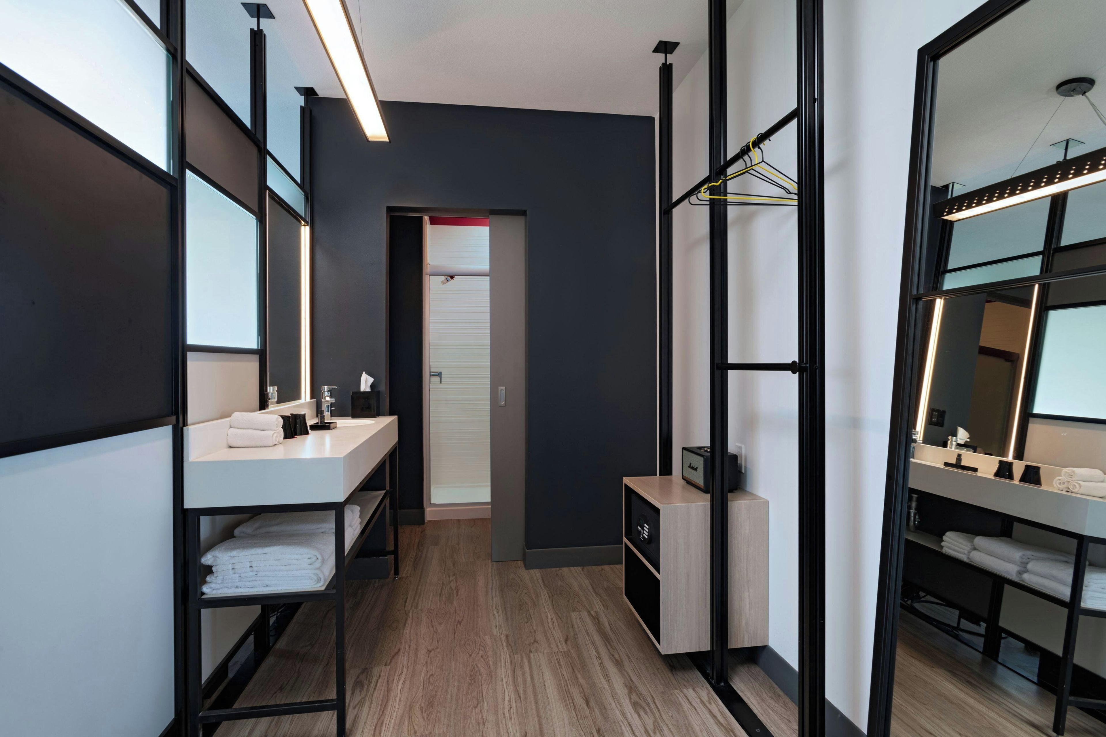 Un baño moderno con tocador, espejo y toallero.
