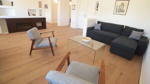 A modern living room with a dark grey sofa, two armchairs, a glass coffee table, and a fireplace. - Beautiful apartment in the center of Rome (Roma)