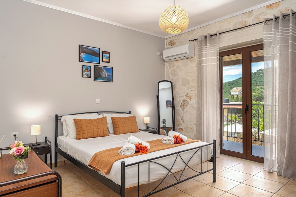 A hotel room with a bed, bedside tables, a mirror, and a view of the outdoors.