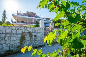 A modern house with a stone wall, a balcony, and lush greenery. - Paradiso Del Mare (Zakynthos)