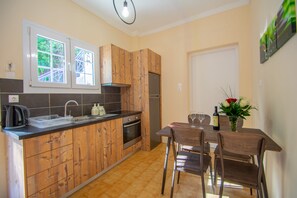 A kitchen with wooden cabinets, a stainless steel refrigerator, and a dining table with chairs. - Paradiso Del Mare (Zakynthos)