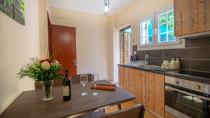 Una cocina moderna con armarios de madera, horno empotrado y comedor con mesa y sillas de madera.