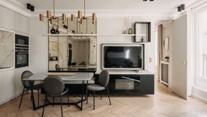 A modern kitchen with a dining area, a large flat-screen TV, and a built-in oven. -  HIGHSTAY - Luxury Serviced Apartments - Rue de Rivoli (Paris)
