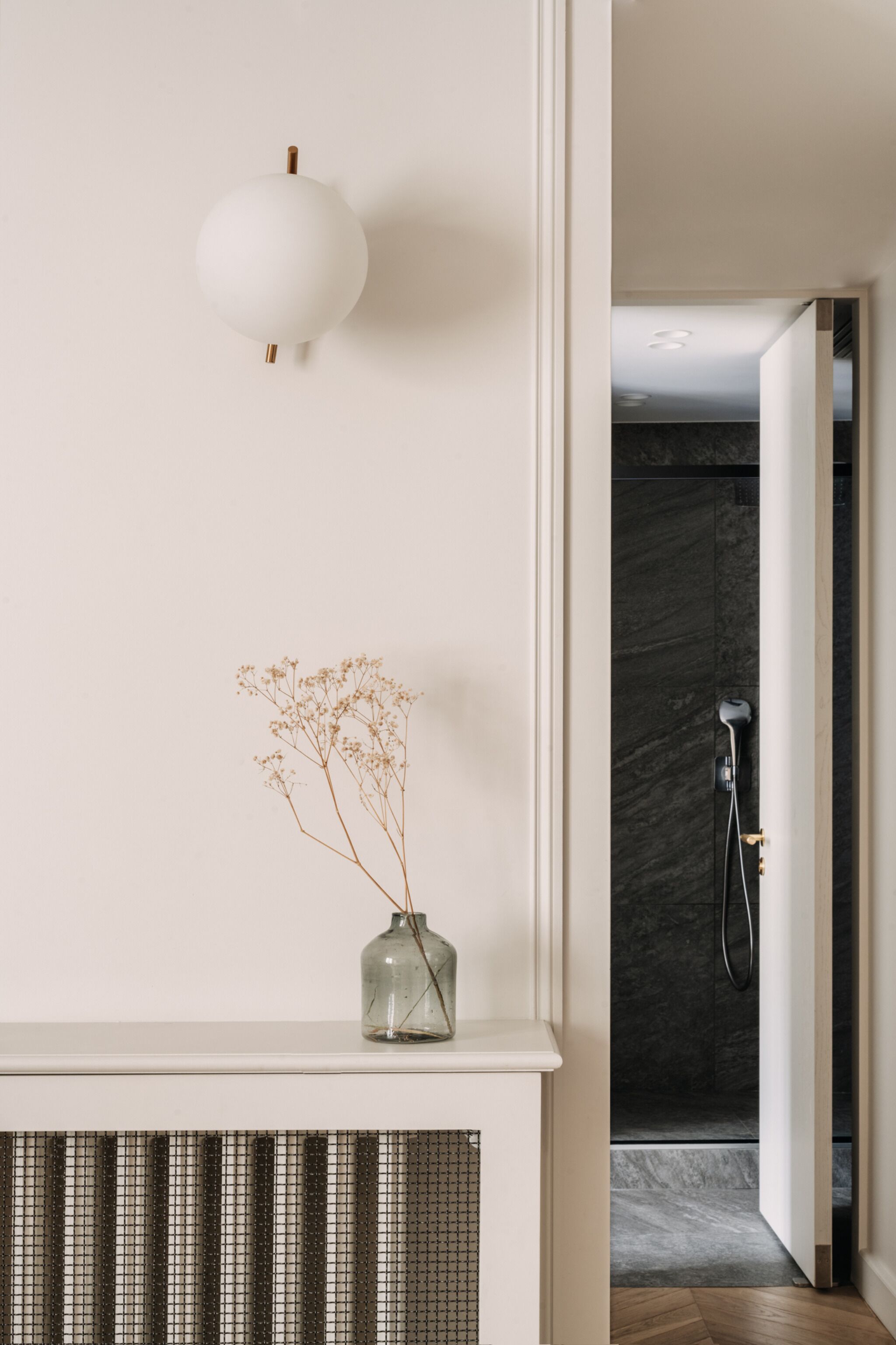 A bathroom with a shower, a white wall, and a radiator.