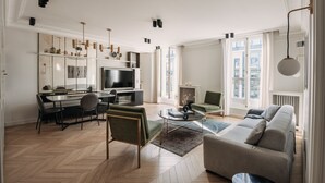 A modern living room with a sofa, coffee table, and dining area. -  HIGHSTAY - Luxury Serviced Apartments - Rue de Rivoli (Paris)