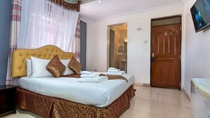 A bedroom with a bed, a wooden door, and a television on the wall. - Milele Resort Nakuru (Nakuru)