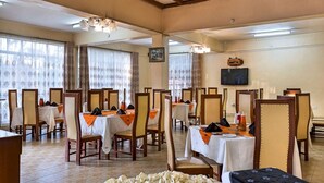 A dining area with tables set for service, chairs, and a television mounted on the wall. - Milele Resort Nakuru (Nakuru)