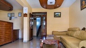 A spacious living area with a wooden coffee table, a beige sofa, and a staircase leading to another floor. - Milele Resort Nakuru (Nakuru)