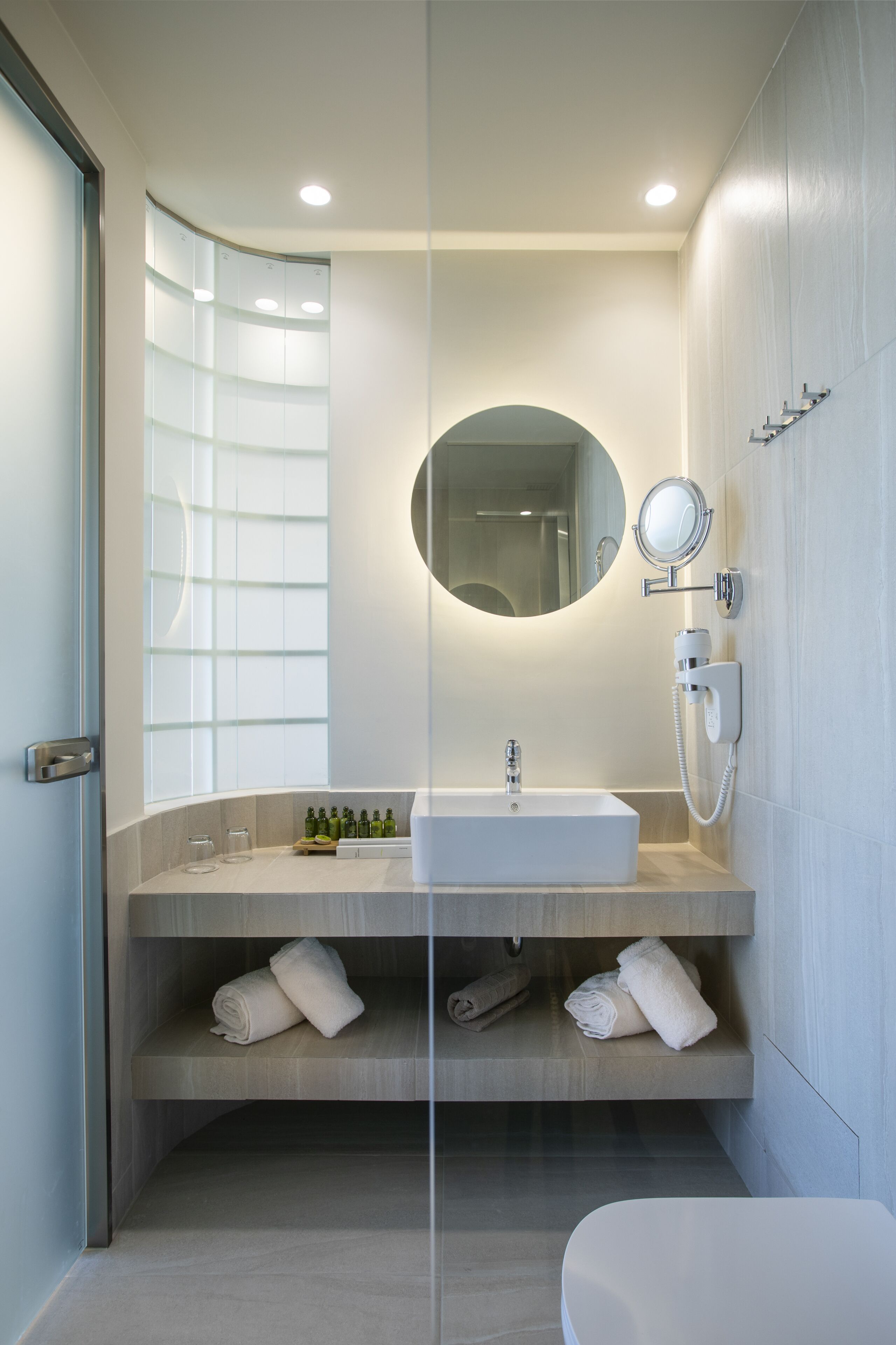 Un baño moderno con un lavamanos blanco, un espejo y un perchero para toallas.
