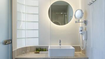 Un baño moderno con un lavamanos blanco, un espejo y un perchero para toallas.