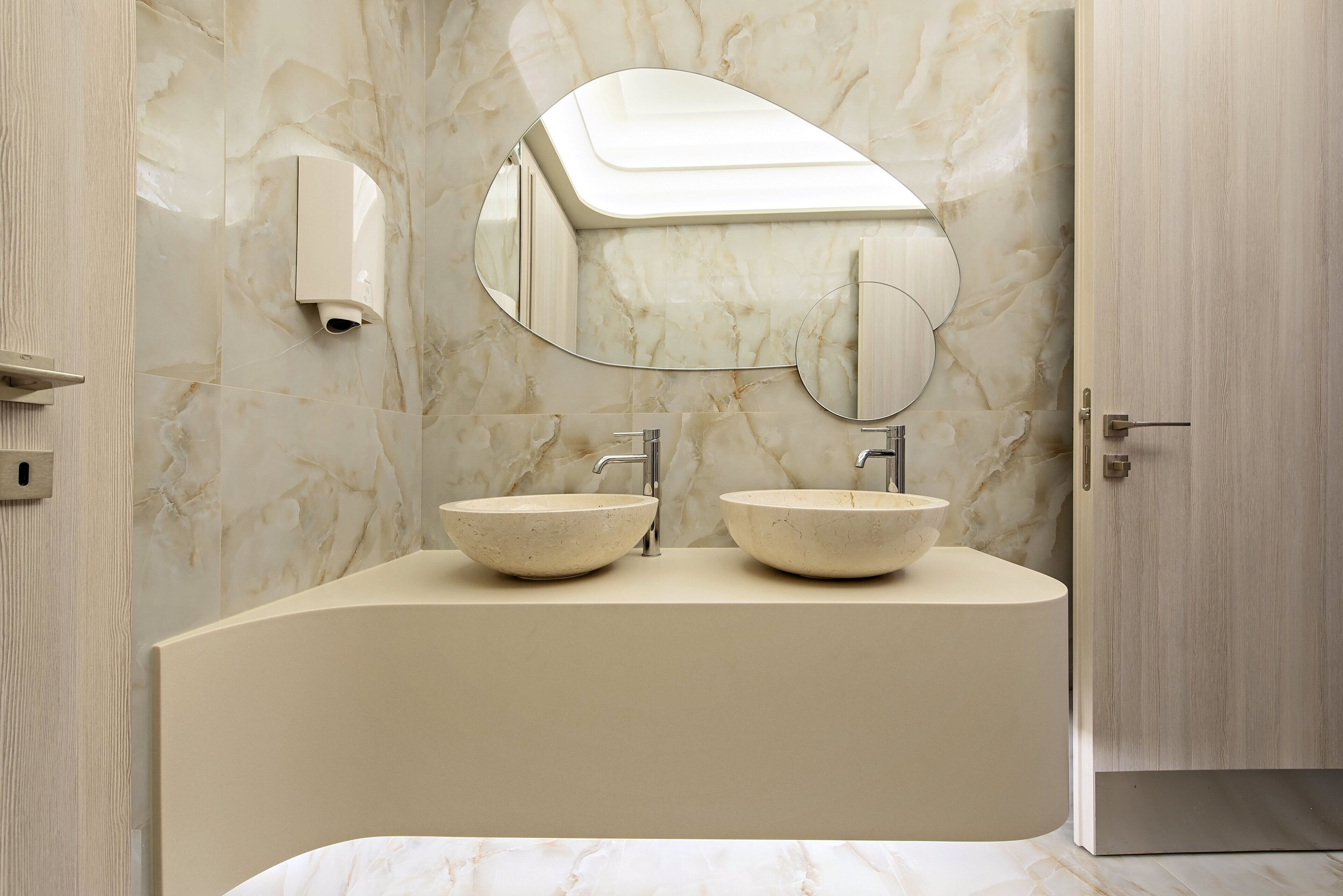 A bathroom with two sinks, a mirror, and a hand dryer.