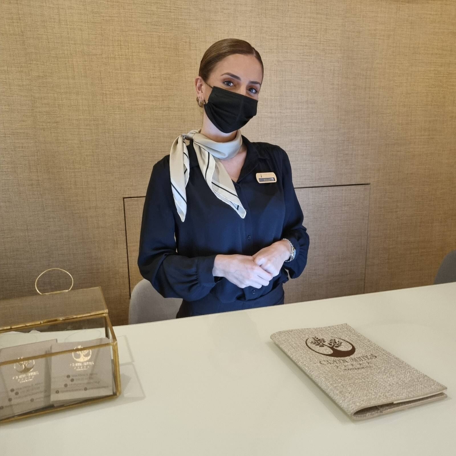 A hotel reception area with a reception desk, a name tag, and a brochure on the table.