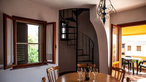 A dining area with a wooden table, chairs, and a spiral staircase. - FANTASTICO PORTO OTTIOLU (Budoni)