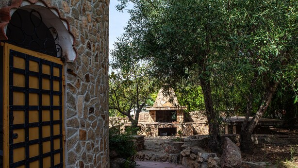 A stone building with a yellow door and a stone wall. - FANTASTICO PORTO OTTIOLU (Budoni)