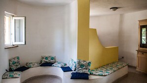 A room with a curved bench, a window, and a yellow accent wall. - FANTASTICO PORTO OTTIOLU (Budoni)