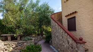 A stone pathway leading to a building with a window and a stone wall. - FANTASTICO PORTO OTTIOLU (Budoni)