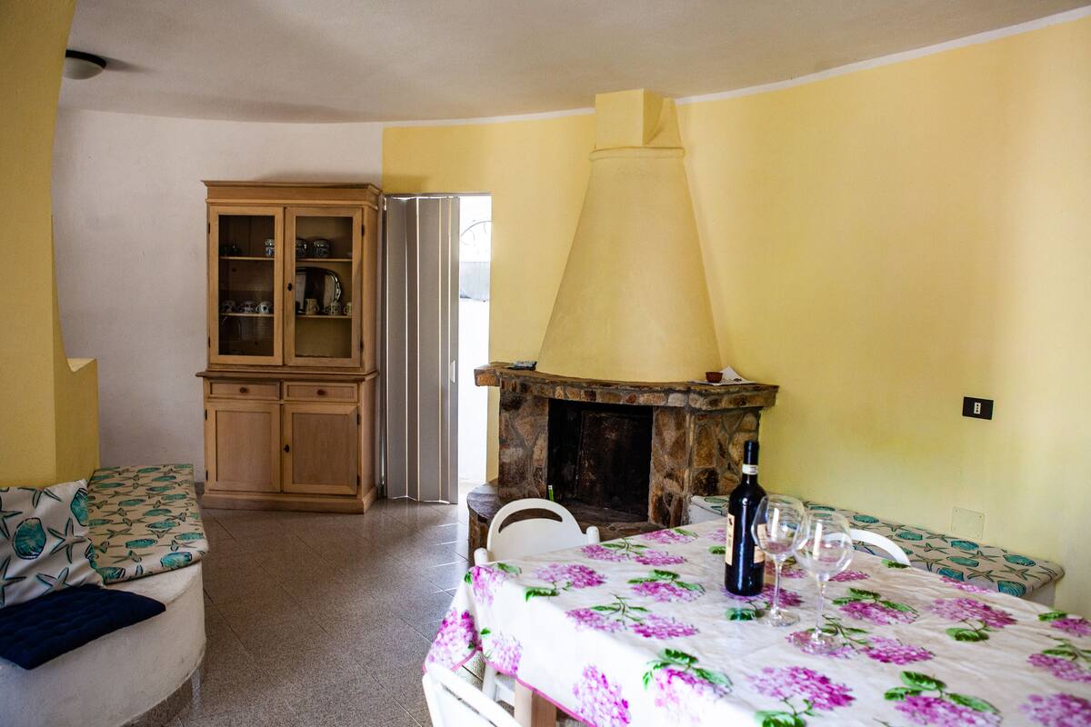 A dining area with a table set for two, a stone fireplace, and a wooden cabinet with glass doors.