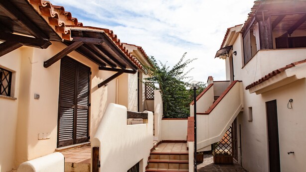 A narrow alleyway with a staircase leading to a building with a tiled roof and wooden beams. - FANTASTICO PORTO OTTIOLU GR1 (Budoni)