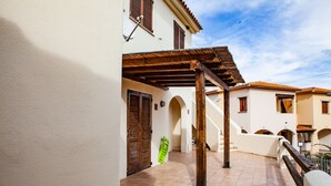 A courtyard with a tiled floor, wooden pergola, and a green object leaning against a wall. - FANTASTICO PORTO OTTIOLU GR1 (Budoni)