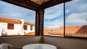 A balcony with a round table and two chairs, overlooking a building with orange tiled roofs and satellite dishes. - FANTASTICO PORTO OTTIOLU GR1 (Budoni)